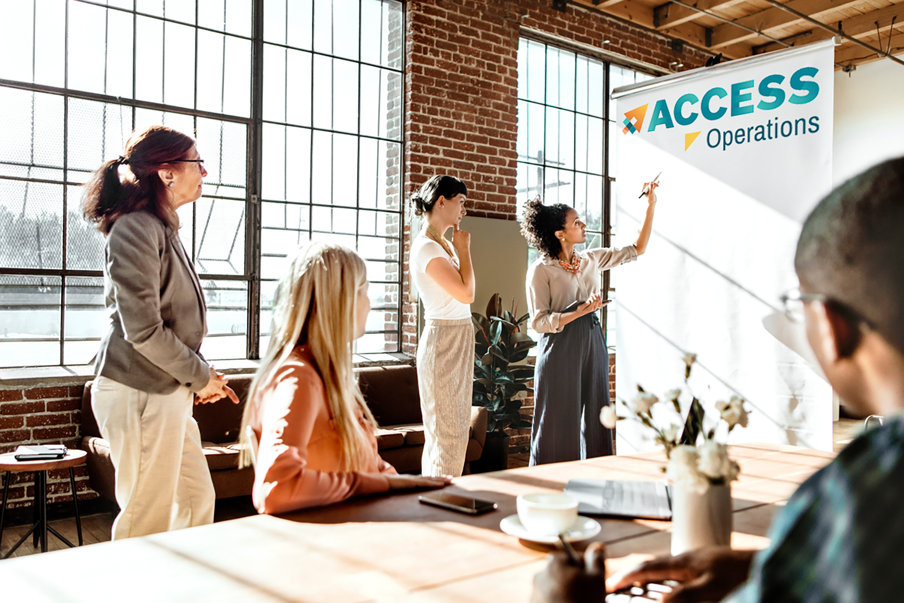 A diverse group of people working on a project together. The ACCESS logo is on a large white pad of paper.