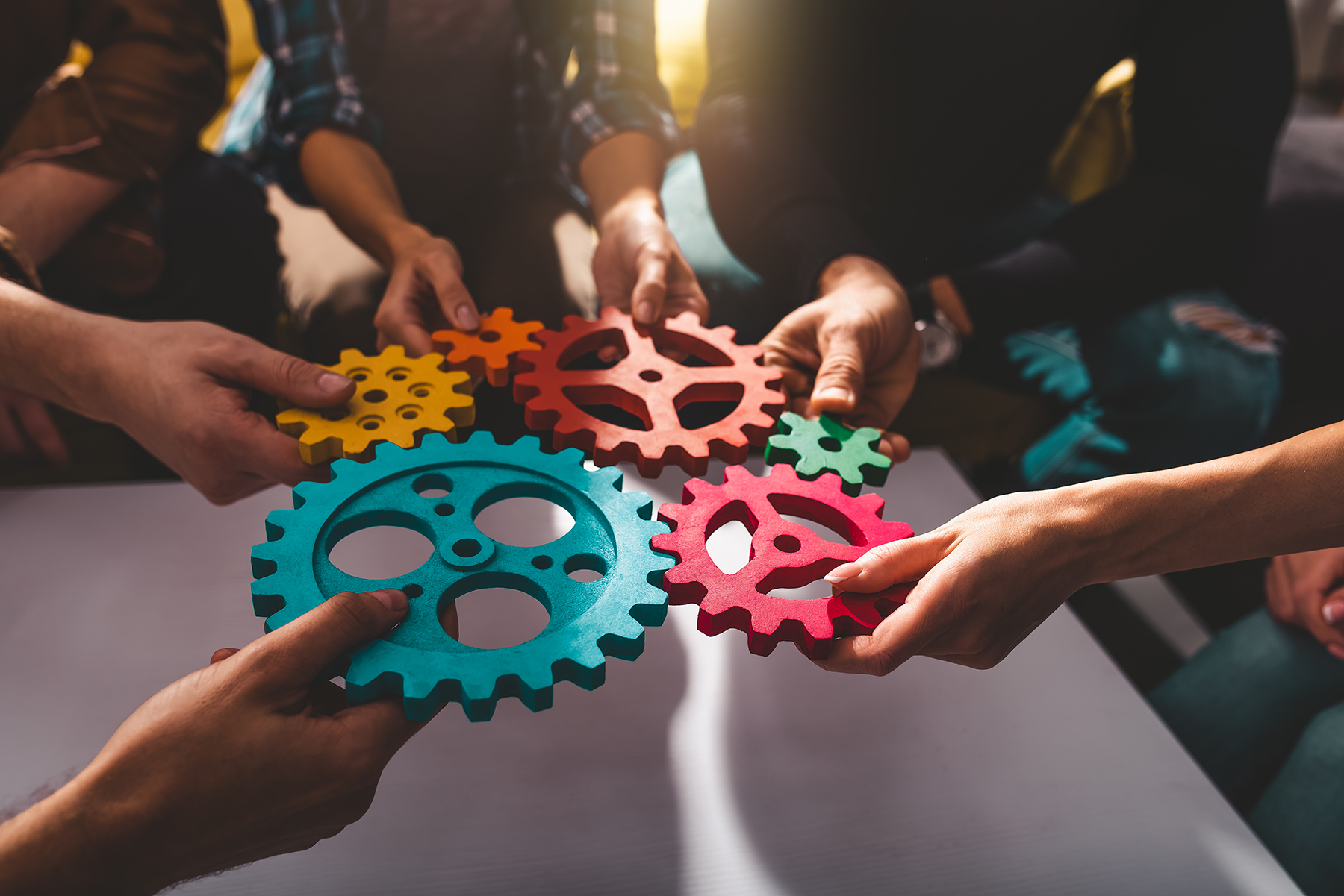 A picture of a team connecting pieces of gears together. Teamwork and integration concept.