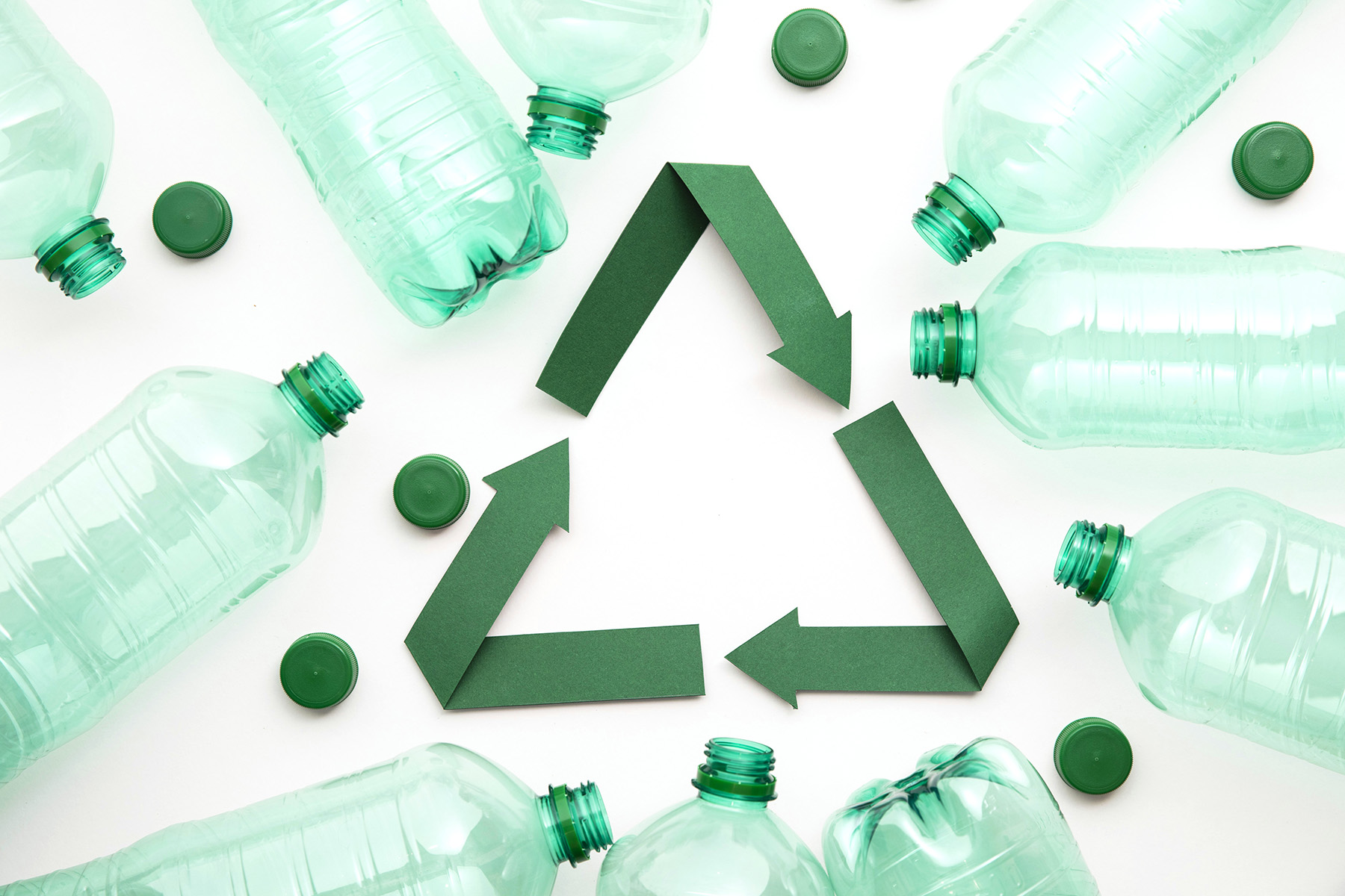 A green paper recycling symbol with empty plastic water bottles surrounding it.